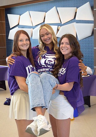Lakeside senior cheerleaders Savannah Ligon, at left, and Jordyn Grace Shibest hoist Karson Babb after signing their national letters of intent to cheer for the University of Central Arkansas on Friday. (The Sentinel-Record/Donald Cross)